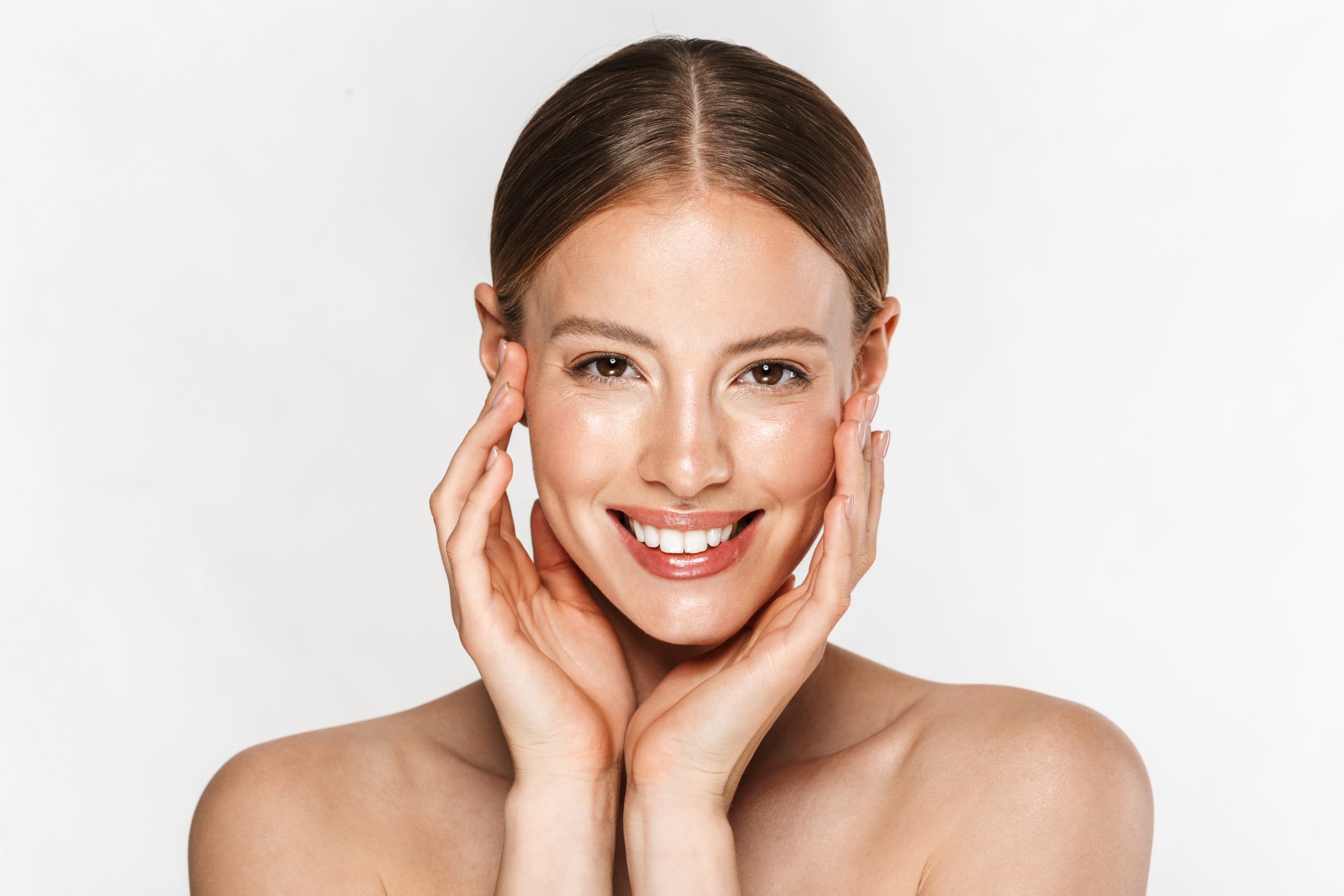 Image of beautiful half-naked woman smiling at camera and touching her face a girls face after receiving her first botox cosmetic